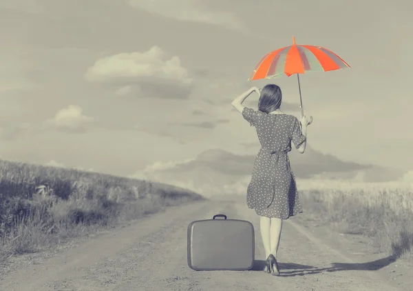 Redhead girl with umbrella and suitcase at outdoor — Stock Photo, Image