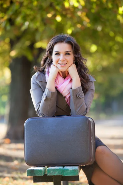 Girl with suitcase at autumn outdoor. — Stockfoto