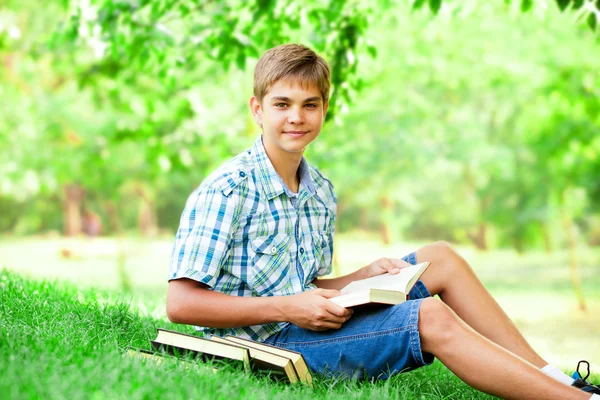 Tiener jongen met boeken en notebook in het park. — Stockfoto