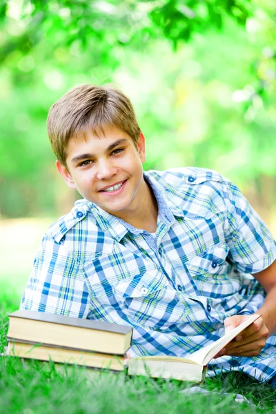 Jeune garçon avec des livres et un cahier dans le parc . — Photo