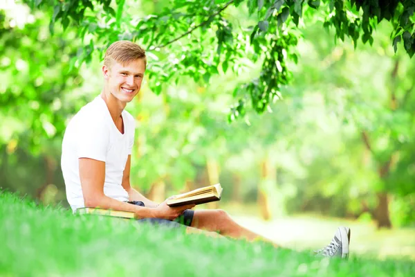 Tiener jongen met boeken en notebook in het park. — Stockfoto