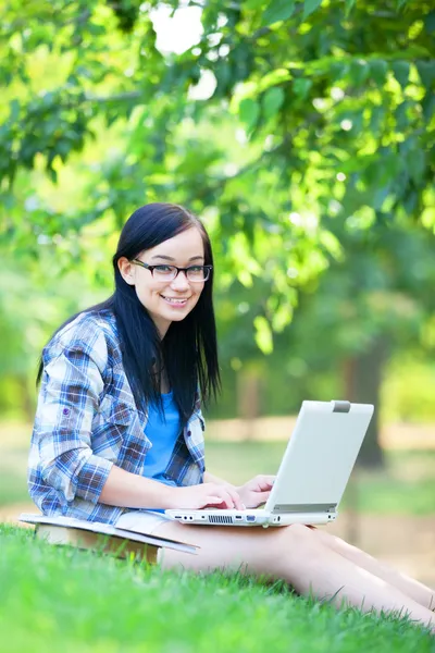 Teen girl with laptop in the park. Royalty Free Stock Images