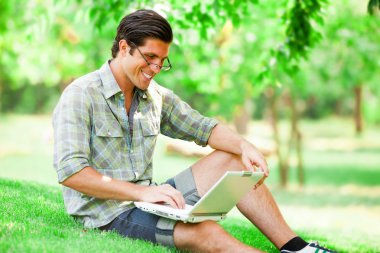 Yeşil çimlerde dizüstü bilgisayarı olan öğrenci