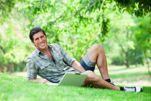 Student met laptop op groen gras — Stockfoto