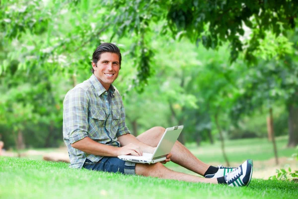 Estudiante con portátil en hierba verde — Foto de Stock