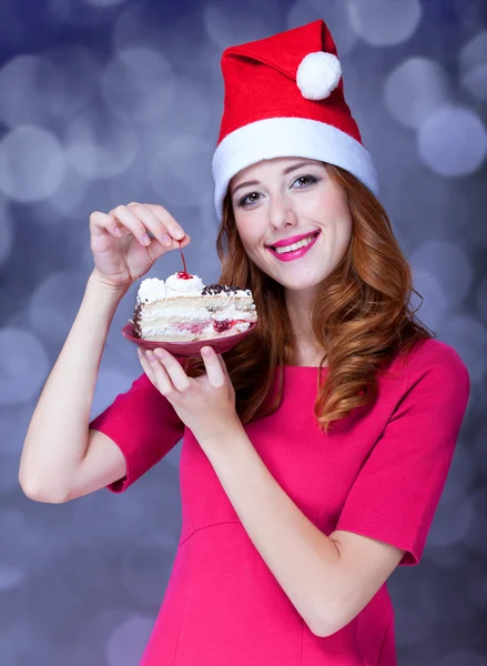 Redhead girl in christmas hat with cake — Stock Photo, Image