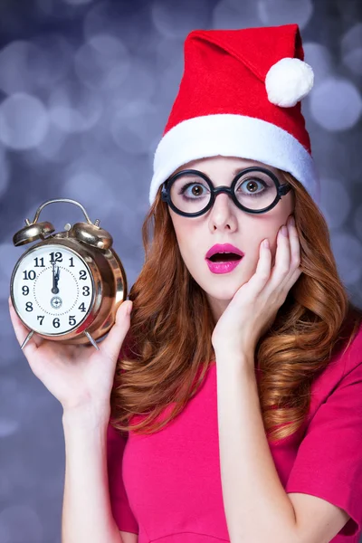 Redhead girl in christmas hat with clock — Stock Photo, Image