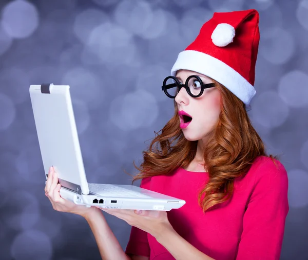 Rothaarige Mädchen mit Weihnachtsmütze und Laptop — Stockfoto