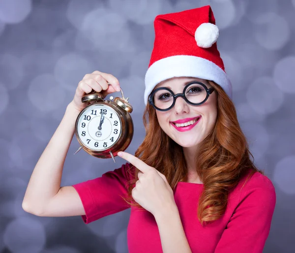 Redhead girl in christmas hat with clock — Stock Photo, Image