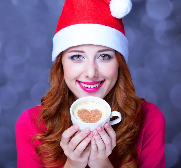 Руда дівчина в різдвяному капелюсі з чашкою кави — стокове фото