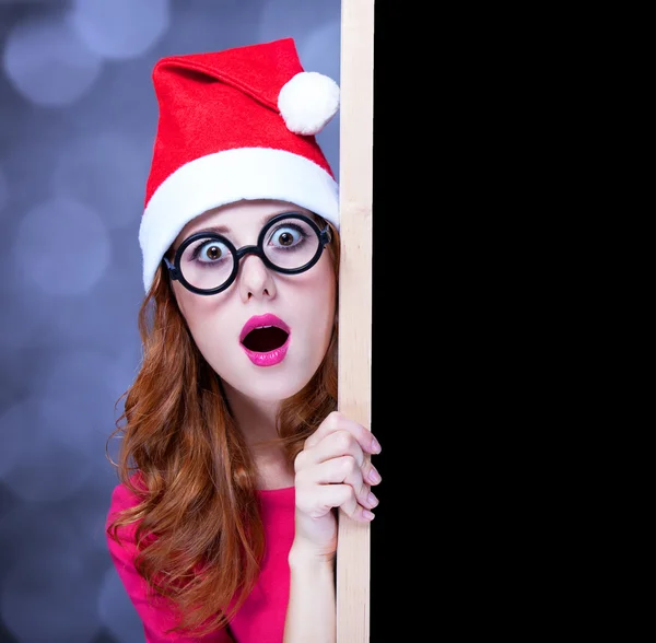 Menina ruiva em chapéu de Natal com quadro negro — Fotografia de Stock