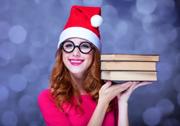 Menina ruiva em chapéu de Natal com livros — Fotografia de Stock