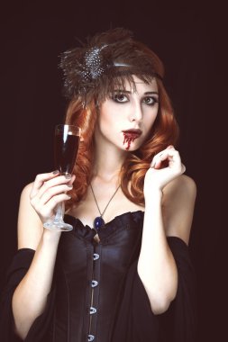 Kızıl saçlı vampir kanı bardak kadınla. fotoğrafta vintage styl