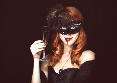 Kızıl saçlı vampir kadın maskesi ile cam kan içinde.