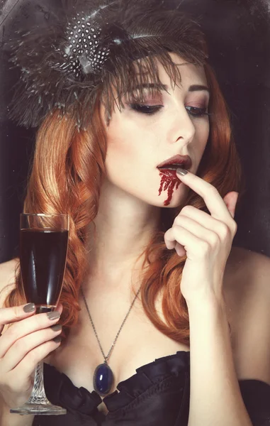 Redhead vampier vrouw met glas van bloed. foto in vintage styl — Stockfoto