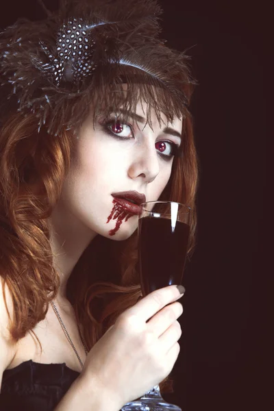 Rothaarige Vampirfrau mit einem Glas Blut. Foto im Vintage-Stil — Stockfoto