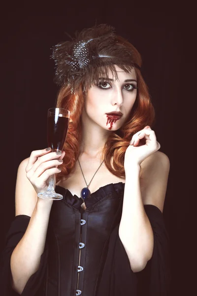Redhead vampire woman with glass of blood. Photo in vintage styl — Stock Photo, Image