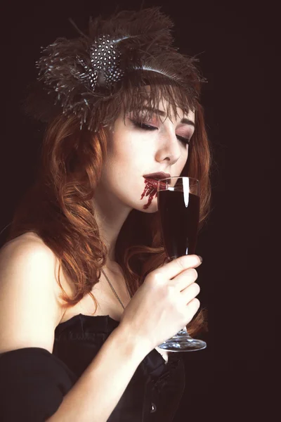 Mujer vampiro pelirroja con vaso de sangre. Foto en estilo vintage —  Fotos de Stock