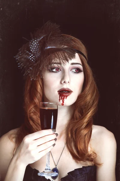 Redhead vampire woman with glass of blood. Photo in vintage styl — Stock Photo, Image