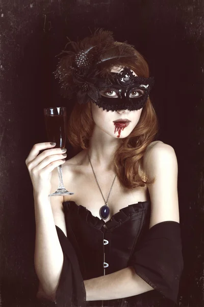 Pelirroja vampiro mujer en máscara con vaso de sangre . —  Fotos de Stock