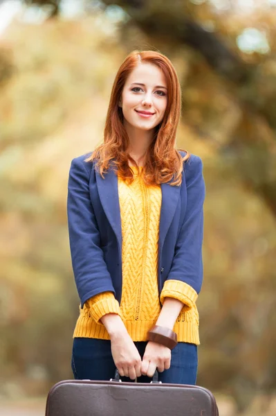 Girl with suitcase at autumn outdoor — Stockfoto