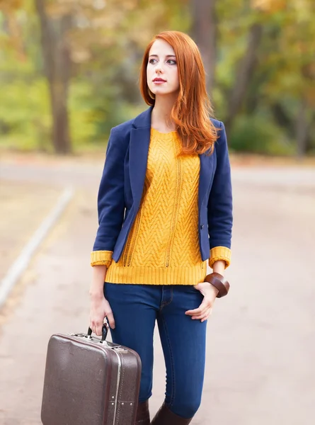 Girl with suitcase at autumn outdoor — Stockfoto