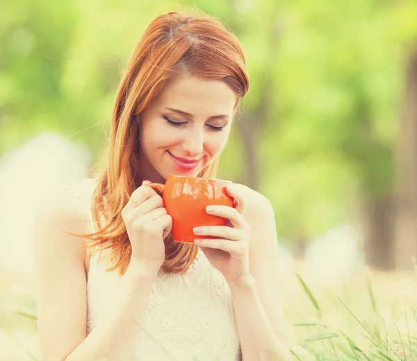 Ragazza rossa con tazza arancione all'aperto — Foto Stock