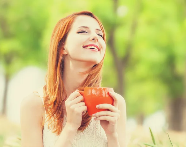 Rothaarige Mädchen mit orangefarbener Tasse im Freien — Stockfoto