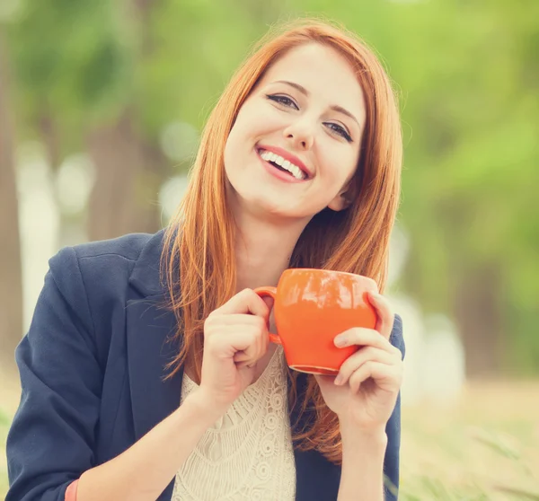 Rothaarige Mädchen mit orangefarbener Tasse im Freien — Stockfoto