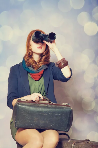 Pelirroja con binocular sentada en la maleta grande —  Fotos de Stock