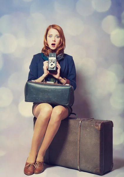 Roodharige meisje met camera zittend op de grote koffer — Stockfoto