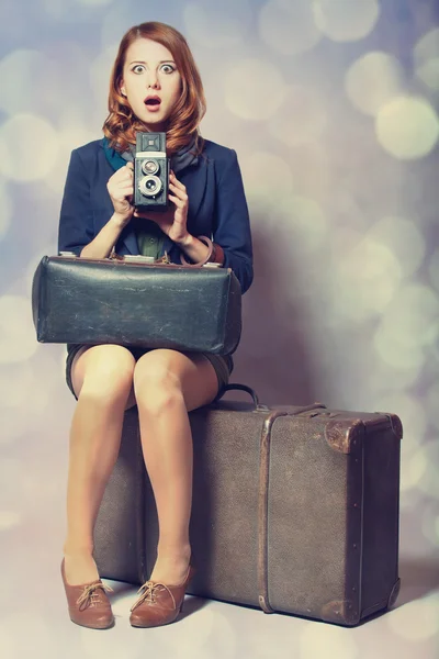 Ragazza rossa con macchina fotografica seduta sulla grande valigia — Foto Stock