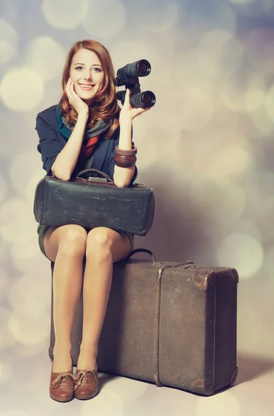 Fille rousse avec binoculaire assis sur la grande valise — Photo