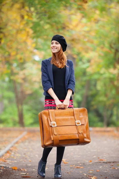 Κοκκινομάλλα κορίτσι με τη βαλίτσα στο φθινόπωρο εξωτερική. — Φωτογραφία Αρχείου