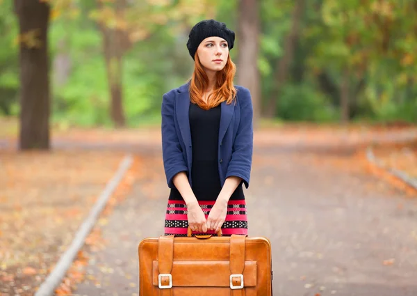 Roodharige meisje met koffer in herfst buiten. — Stockfoto