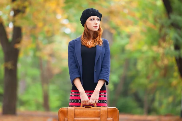 Roodharige meisje met koffer in herfst buiten. — Stockfoto