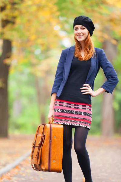 Κοκκινομάλλα κορίτσι με τη βαλίτσα στο φθινόπωρο εξωτερική. — Φωτογραφία Αρχείου