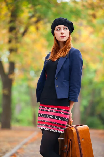 Redhead girl with suitcase at autumn outdoor. — Stock Photo, Image