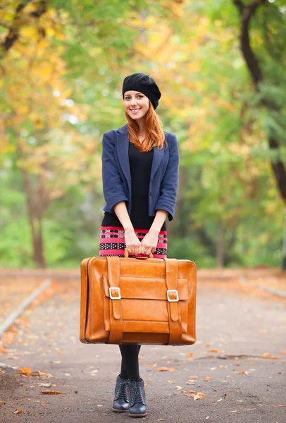 Rusovláska dívka s kufrem na podzim venkovní. — Stock fotografie