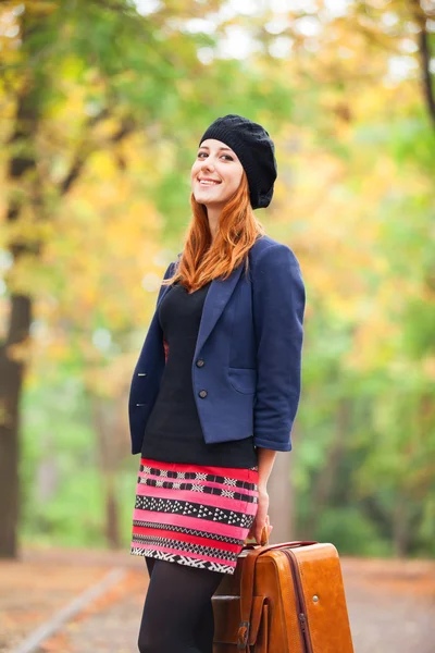 Rothaarige Mädchen mit Koffer im Herbst im Freien. — Stockfoto