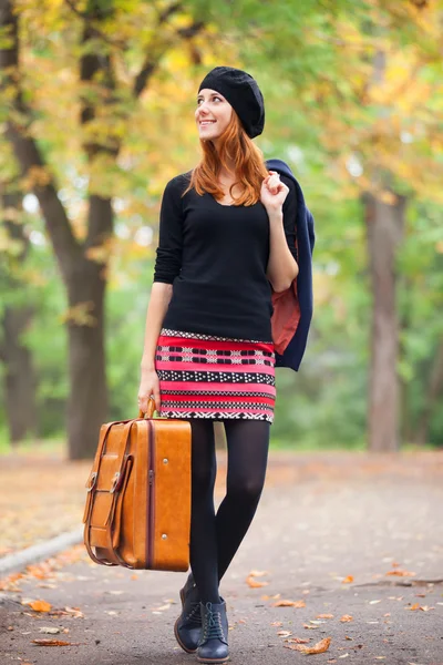 Ragazza rossa con valigia in autunno all'aperto . — Foto Stock