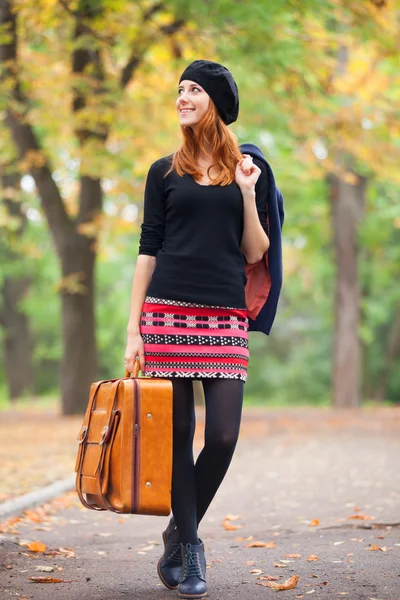 Rothaarige Mädchen mit Koffer im Herbst im Freien. — Stockfoto