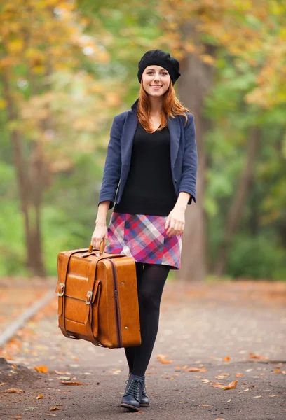 Roodharige meisje met koffer in herfst buiten. — Stockfoto