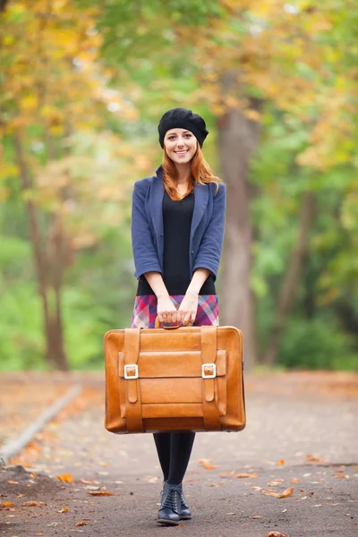 Pelirroja con maleta en otoño al aire libre . — Foto de Stock