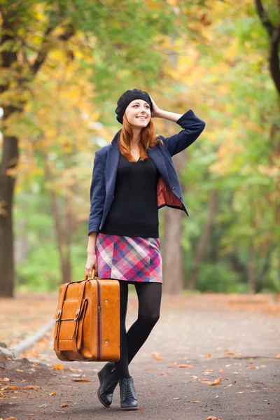 Rödhårig tjej med resväska på hösten utomhus. — Stockfoto