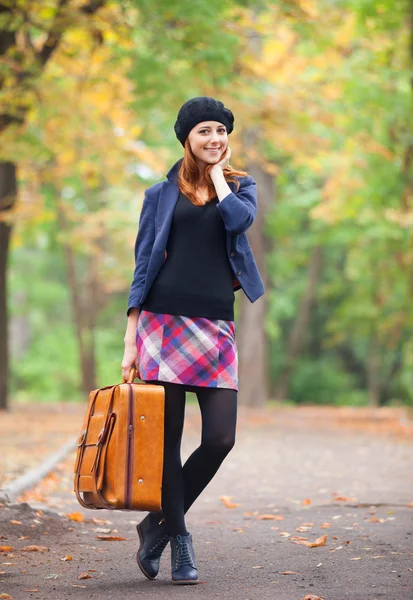 Rothaarige Mädchen mit Koffer im Herbst im Freien. — Stockfoto