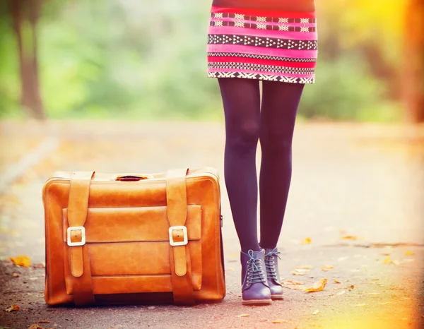 Женские ноги возле чемодана на осеннем открытом воздухе — стоковое фото