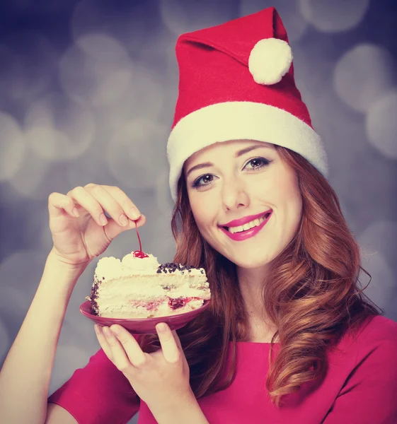 红发女孩在圣诞帽的蛋糕 — 图库照片