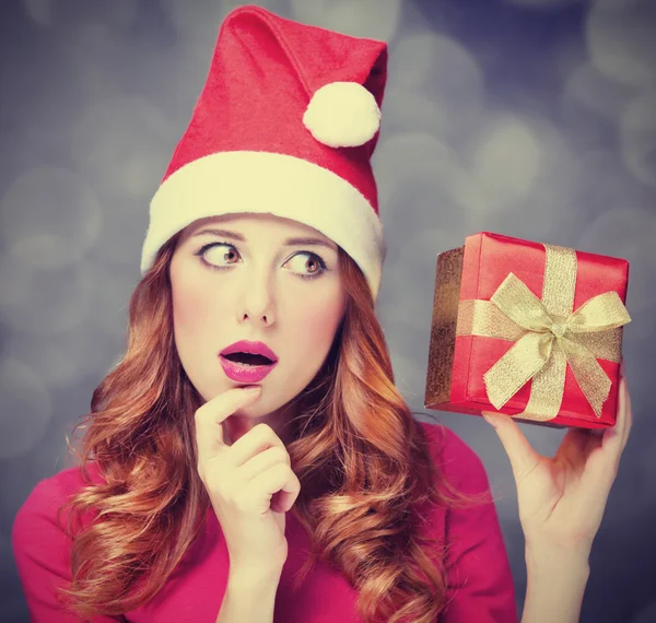 Rothaarige Mädchen mit Weihnachtsmütze und Geschenk. — Stockfoto