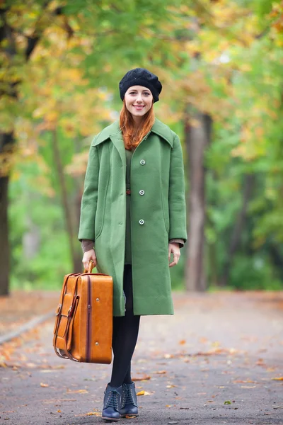 Roodharige meisje met koffer in herfst buiten. — Stockfoto